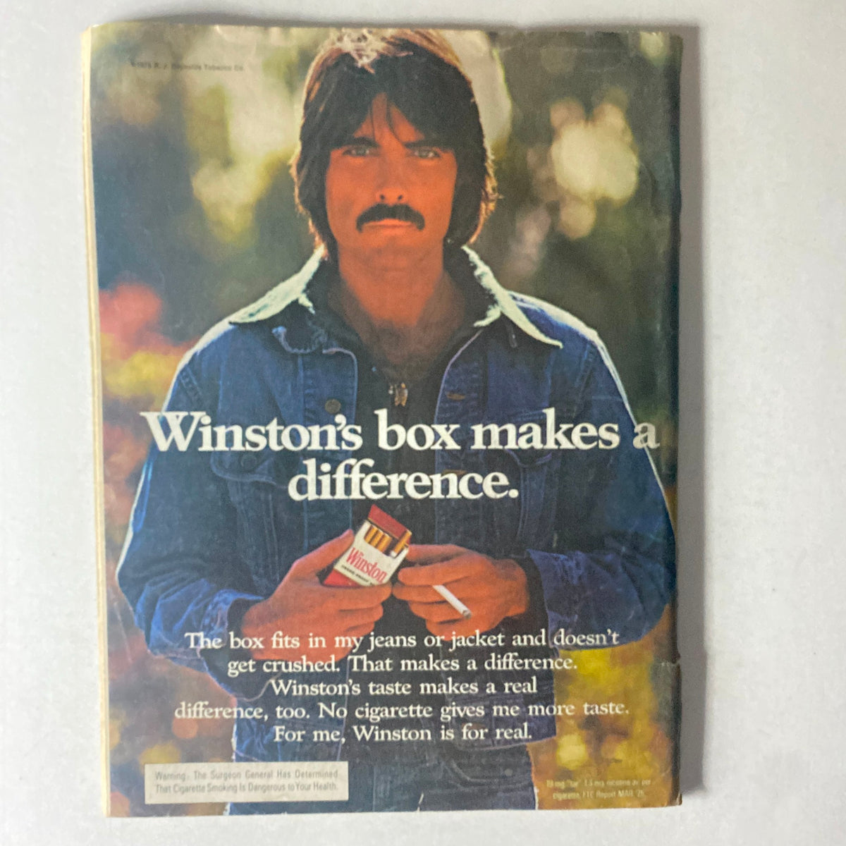 Vintage advertisement in Cycle World Magazine February 1976 featuring a man holding a Winston cigarette box, promoting the product.
