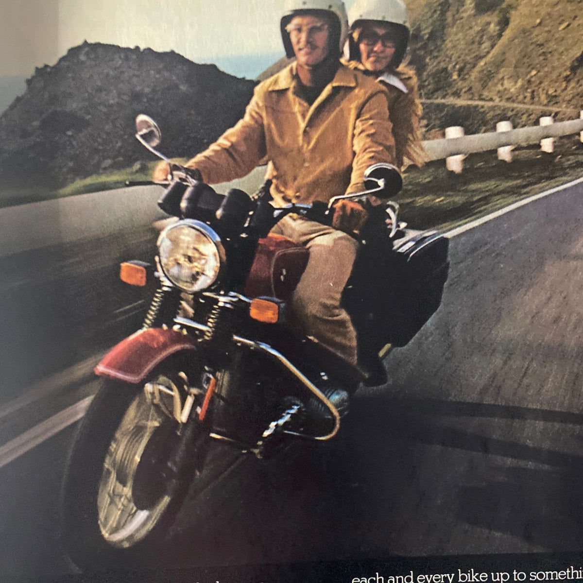 A vintage photograph from Cycle World Magazine December 1975 showing a couple riding a motorcycle on a winding road, representing the adventurous spirit of motorcycling.