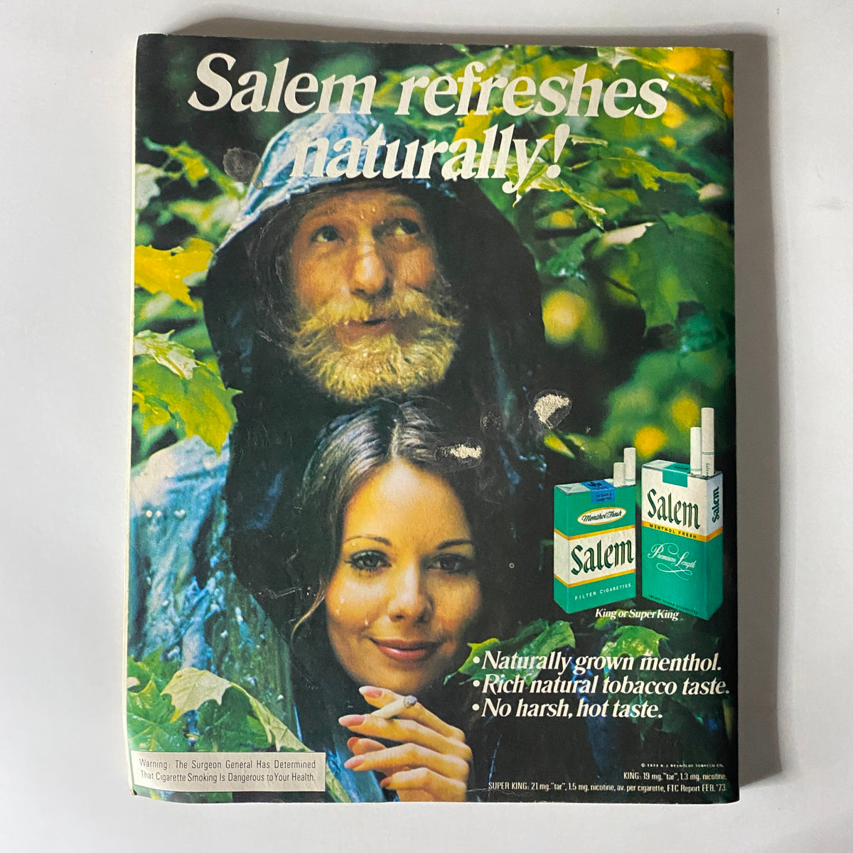 Vintage advertisement from Viva Magazine November 1973 for Salem cigarettes, depicting a man in a raincoat and a woman with a natural look, highlighting the brand's appeal to a young audience.