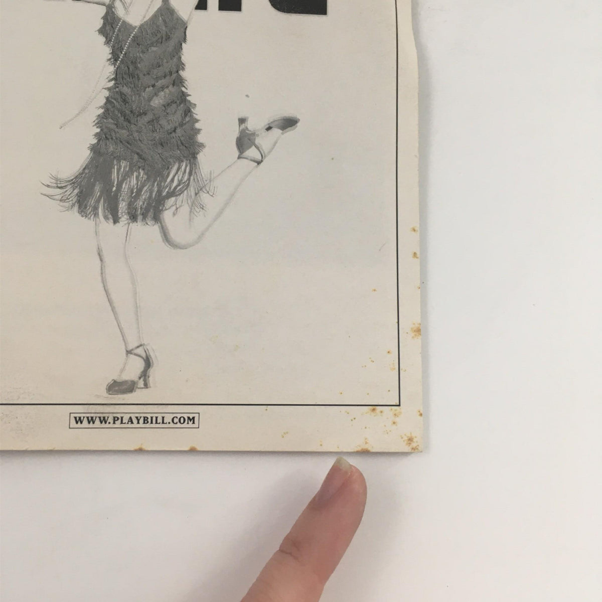 Bottom corner of the 2003 Playbill for Thoroughly Modern Millie showing minor wear, emphasizing its vintage authenticity and connection to a classic Broadway show.
