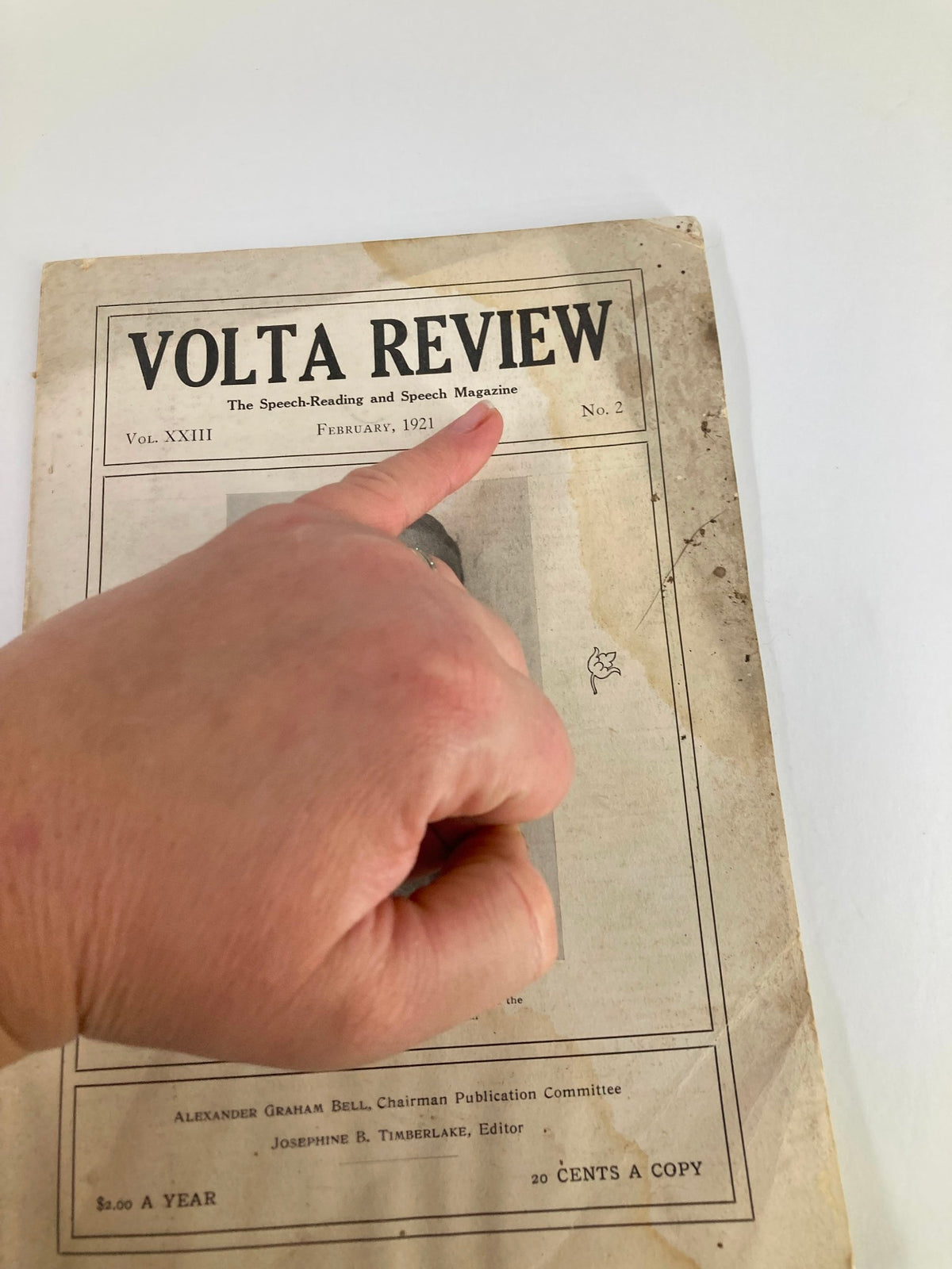 Close-up of the VTG Volta Review Magazine February 1921 cover, showing the issue number and a finger pointing to it, highlighting its historical significance.