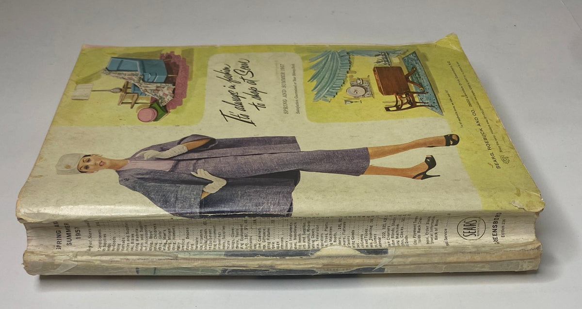 Side view of the 1957 Sears Spring and Summer Catalog, highlighting the vintage style and wear of the cover. The catalog features mid-century fashion and home furnishings illustrations, appealing to collectors of vintage magazines.