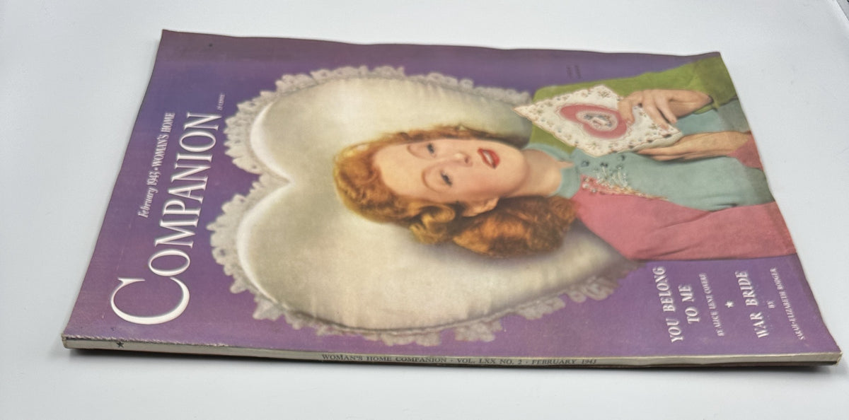 February 1943 Woman’s Home Companion Magazine with a side view of the War Bride cover displaying the title 'You Belong to Me' by Alice Lent Covert, featuring a woman with red hair in a colorful outfit against a heart-themed background.