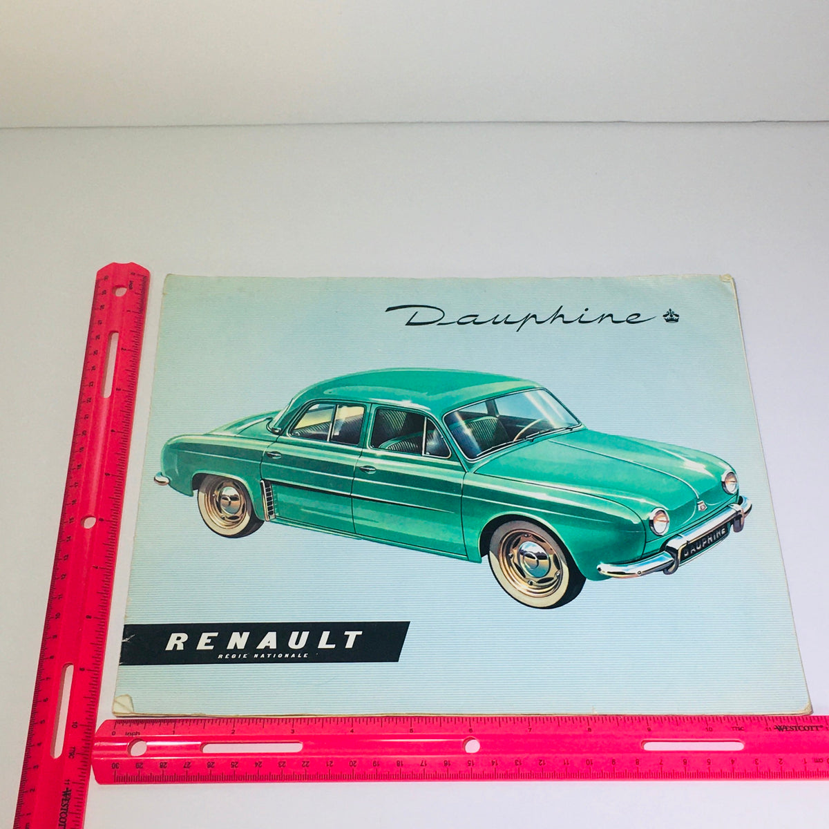 Vintage 1956 Renault Dauphine 4-Speed MT car brochure depicting a green Renault Dauphine, highlighting its unique style and performance in a vintage setting.
