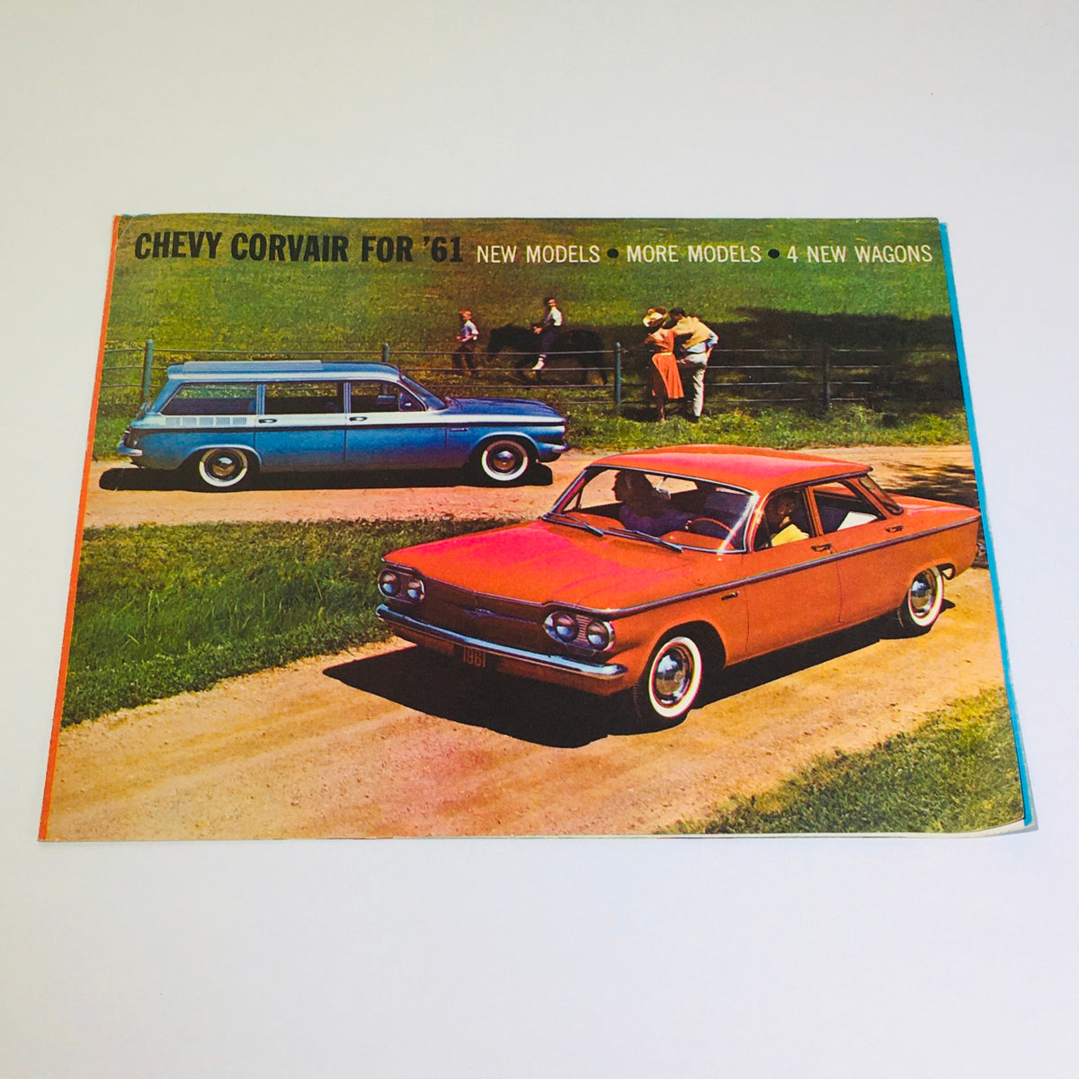 Vintage 1961 Chevy Corvair Wagons and Coupes Monza brochure cover featuring colorful cars on a scenic road, showcasing new models and designs.