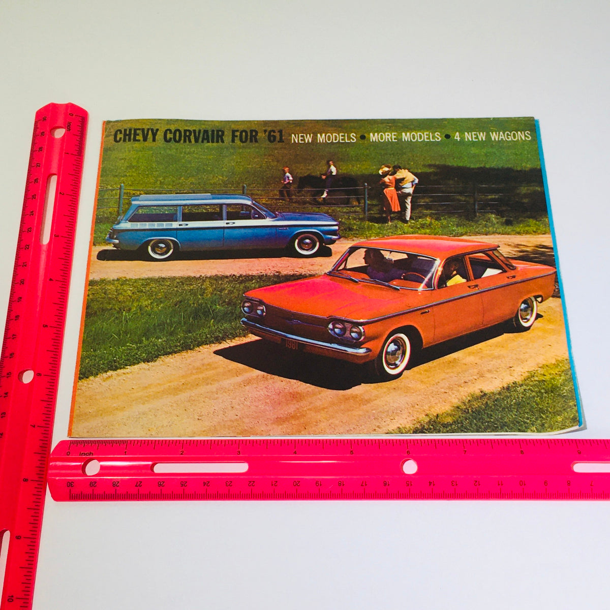 Vintage 1961 Chevy Corvair Wagons Coupes Monza Sports Car Auto Catalog Brochure featuring a blue wagon and a red coupe on a dirt road with green fields in the background.