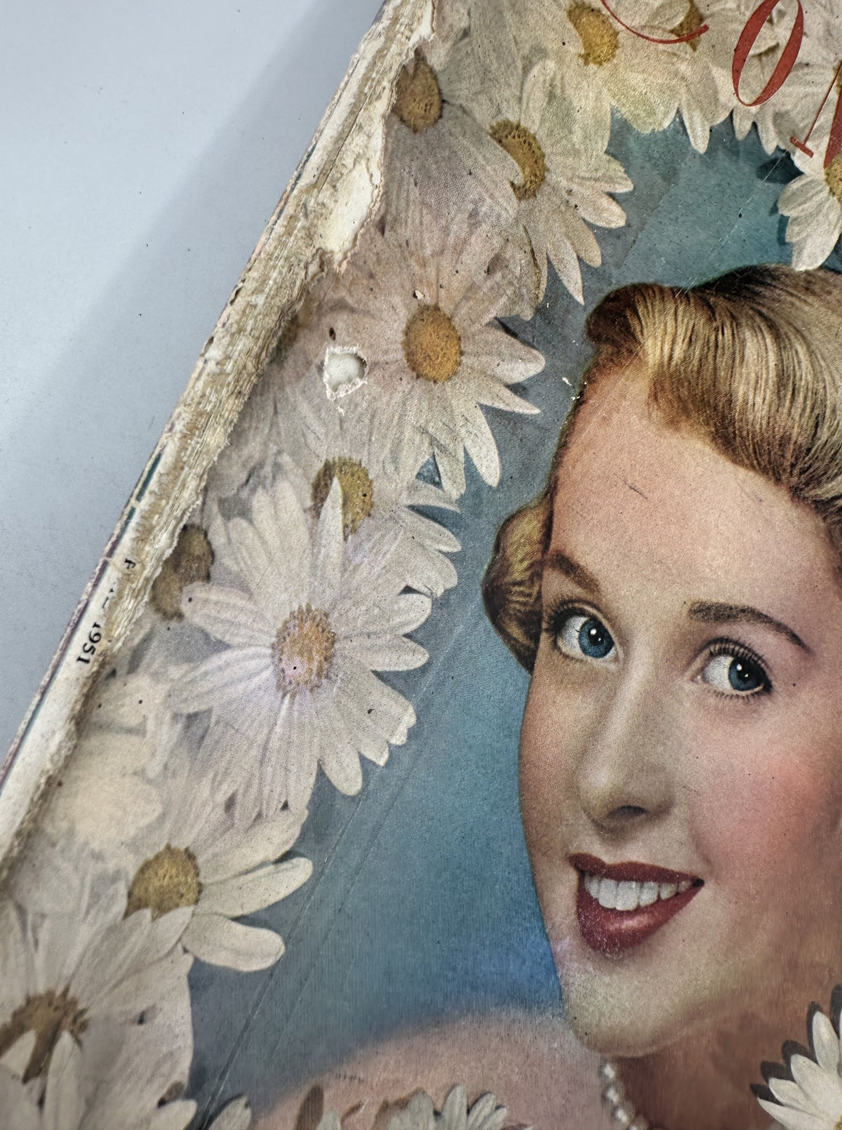 Close-up of the cover of Woman’s Home Companion Magazine April 1951, highlighting the woman's portrait and the floral border, indicating its vintage condition.
