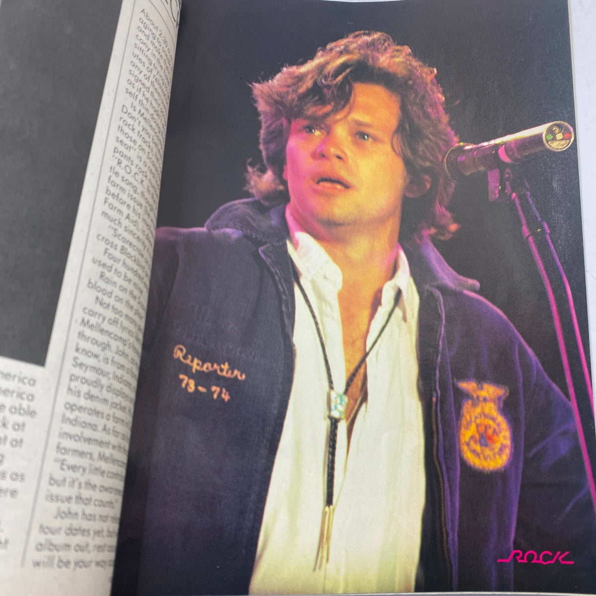 Photo of performer onstage from January 1986 issue of Tiger Beat magazine, featuring a musician in a denim jacket and microphone in hand.