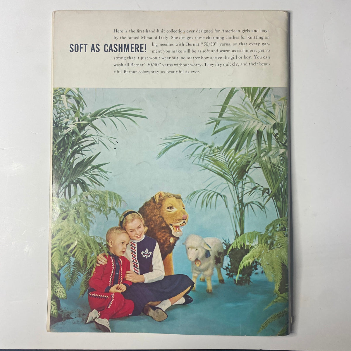 Cover of the 1959 No. 80 Bernat Mirsa of Italy Bulky-Knits Catalog featuring a serene scene with children, a lion, and a sheep amidst lush greenery, highlighting vintage knitwear designs.