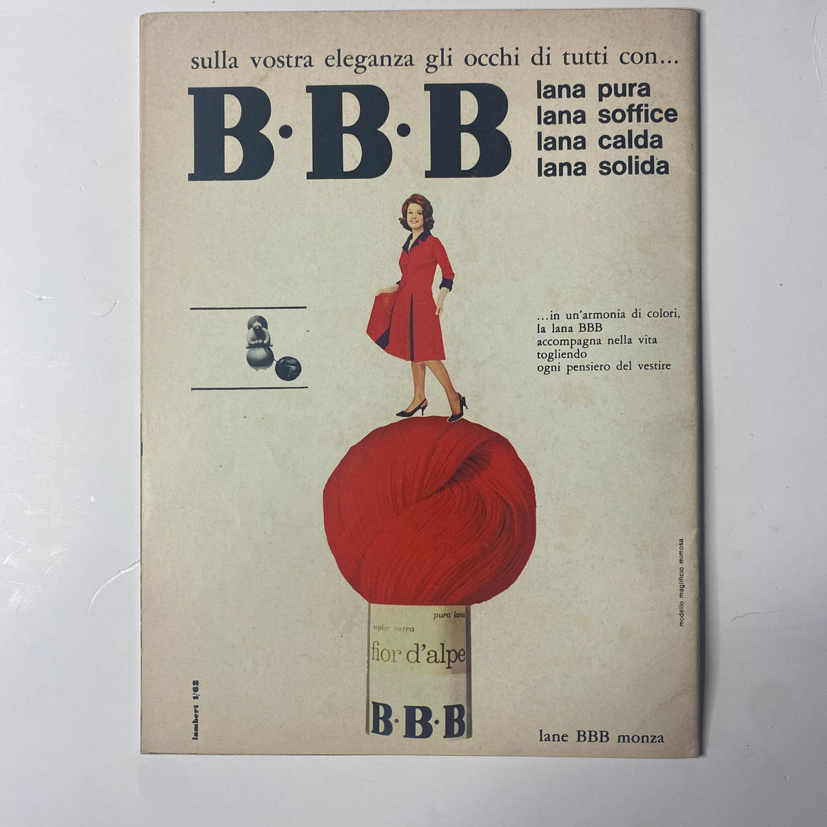 1962 La Moda Dei Bimbi Autumn and Winter Catalog cover page featuring a stylish woman in a red dress standing over a large ball of yarn. The design emphasizes elegance and the theme of childhood fashion in mid-century Italy.