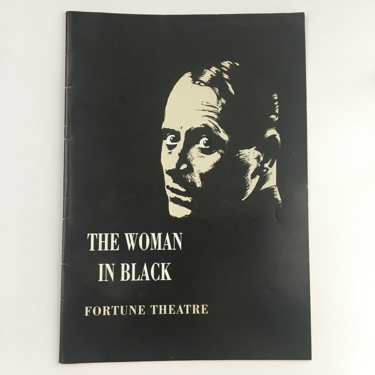 Cover of the 1989 program for 'The Woman in Black' at Fortune Theatre, featuring a striking monochrome illustration of a man's face, and the title prominently displayed.