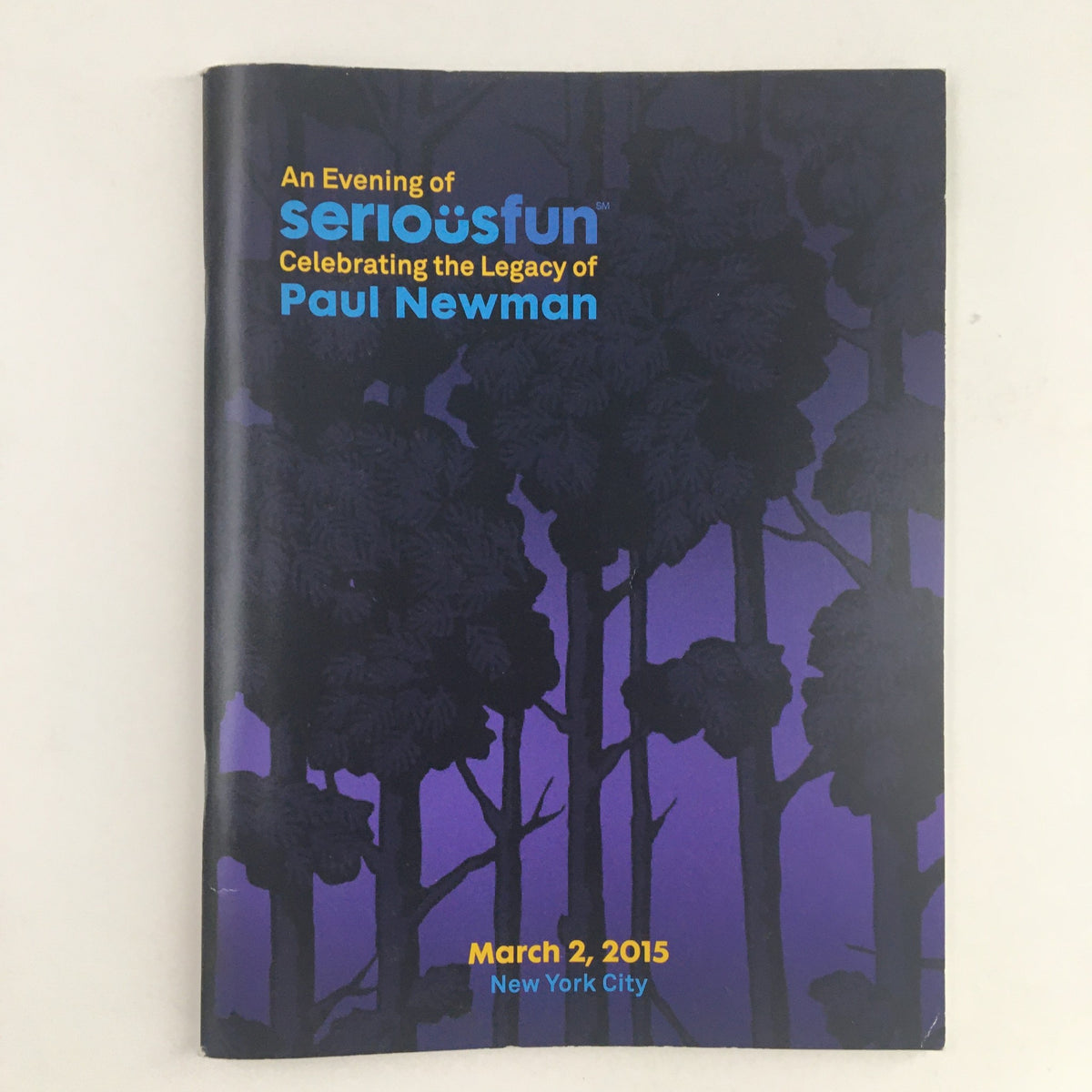 Cover of 'An Evening of Serious Fun Celebrating the Legacy of Paul Newman' event program, featuring artistic trees against a purple background, dated March 2, 2015, New York City. 