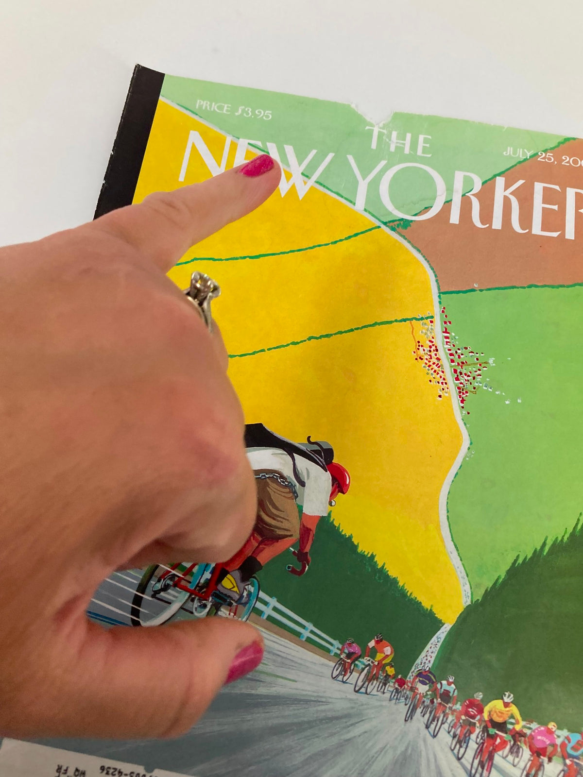 Close-up of The New Yorker cover from July 25, 2005, showing the 'Tour de Force' artwork by Bruce McCall, with a hand pointing to a detail on the cover.