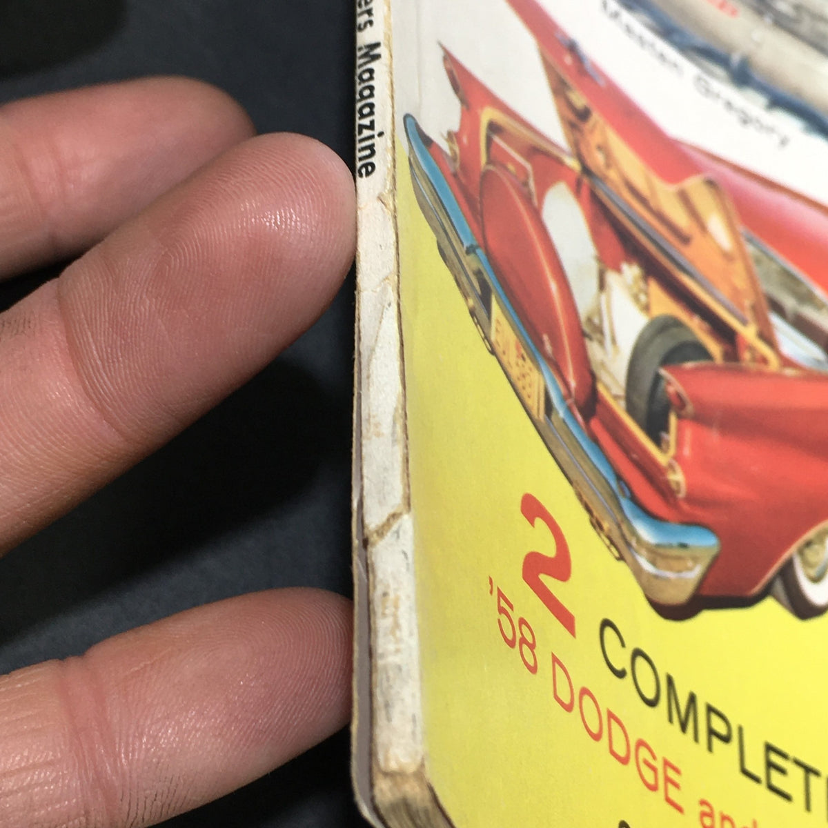 Side view of the Vintage Motor Trend Magazine March 1958, highlighting the magazine's age with wear on the spine and showcasing a red Dodge car illustration.
