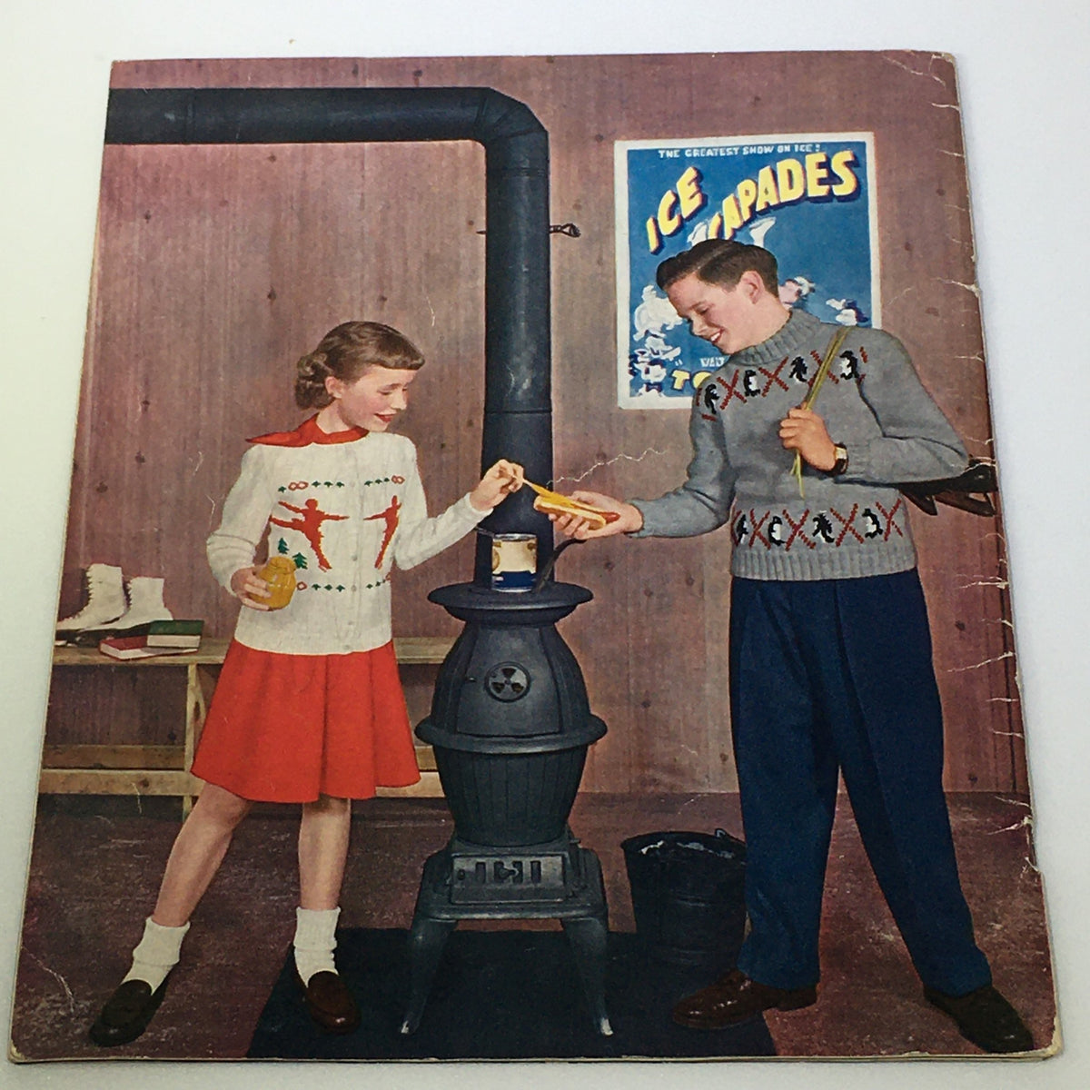 Vintage image from the VTG 1950 Sweet Sue Knitting Catalog depicting a boy and girl engaging in playful activities around a heating stove, showcasing 1950s fashion styles.