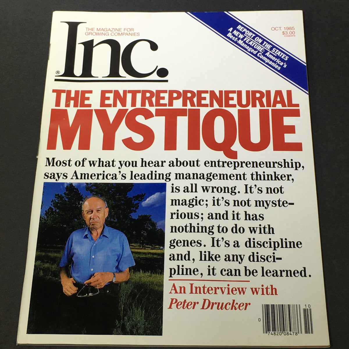 VTG Inc. The Entrepreneurial Mystique October 1985 cover featuring Peter Drucker discussing entrepreneurship, showcasing a portrait of Drucker in a blue shirt, surrounded by nature, with bold text highlighting the magazine's theme.