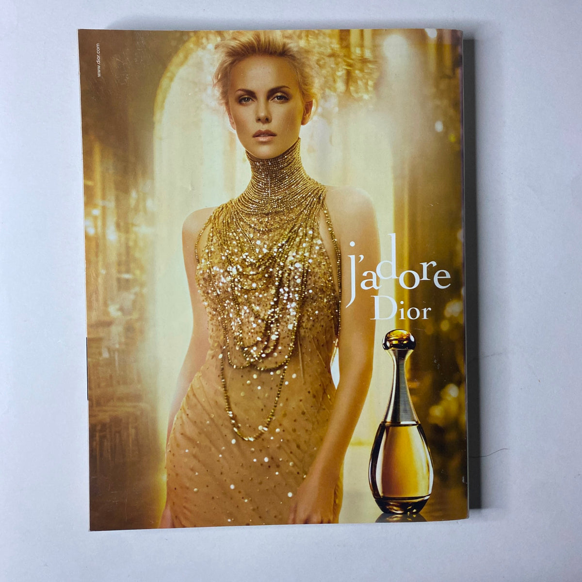 Cover of a Dior advertisement featuring actress Charlize Theron wearing a glamorous golden dress adorned with luxurious pearls, promoting the fragrance 'J'adore', featured in Vogue British Magazine October 2011.