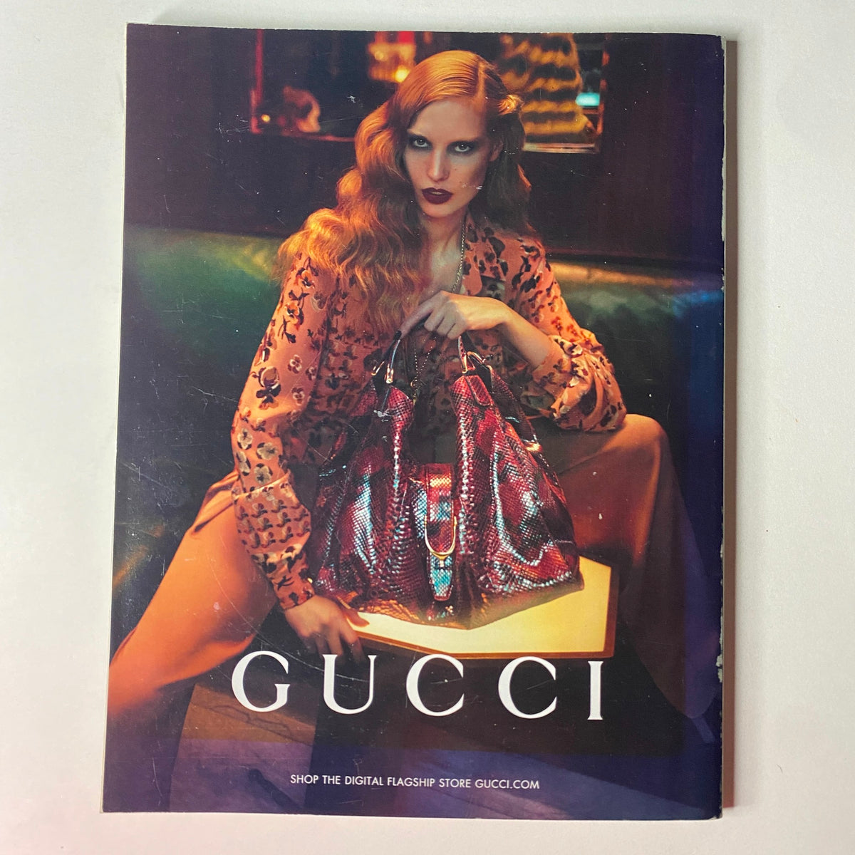 Cover of Gucci advertisement with a glamorous model showcasing stylish handbags, reflecting the luxurious fashion featured in Vogue British Magazine August 2012 with Emma Stone on the cover.