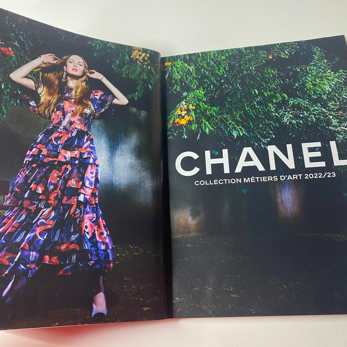 Chanel Collection Métiers d'Art 2022/23 showcasing a model in a vibrant, floral patterned dress, featured in Vogue British Magazine August 2023 with Maya Jama on the cover.
