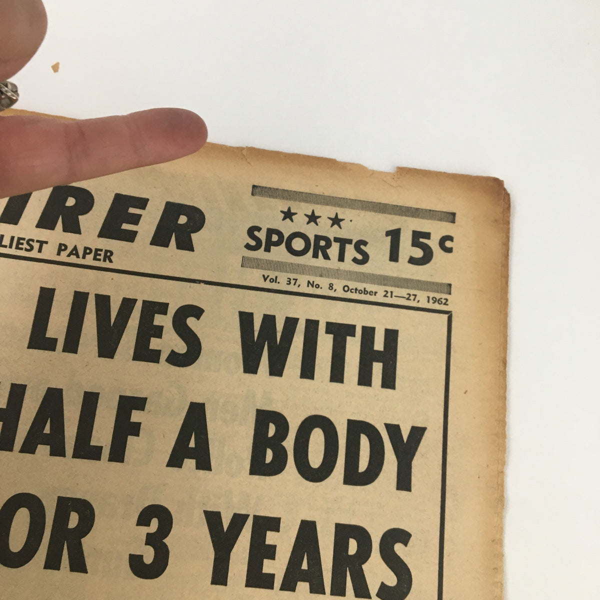 Close-up view of the National Enquirer newspaper dated October 21, 1962, highlighting the headline about a man living with half a body for three years.