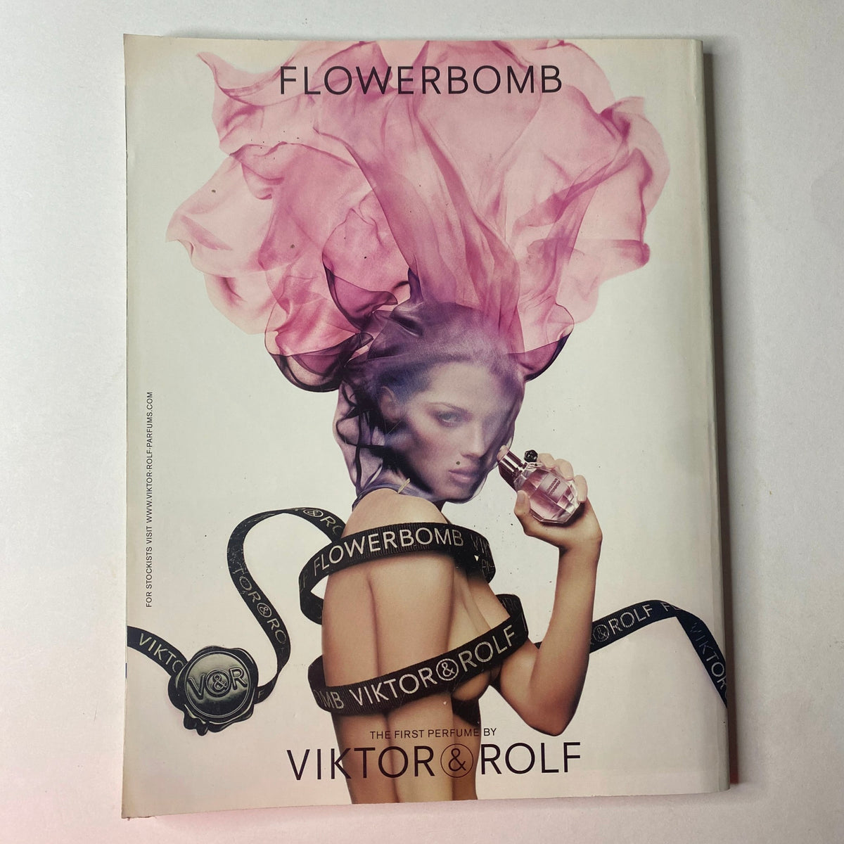 Vogue British Magazine May 2010 cover with Flowerbomb by Viktor & Rolf, displaying a model with flowing pink hair, promoting luxury fragrances in a visually captivating manner.