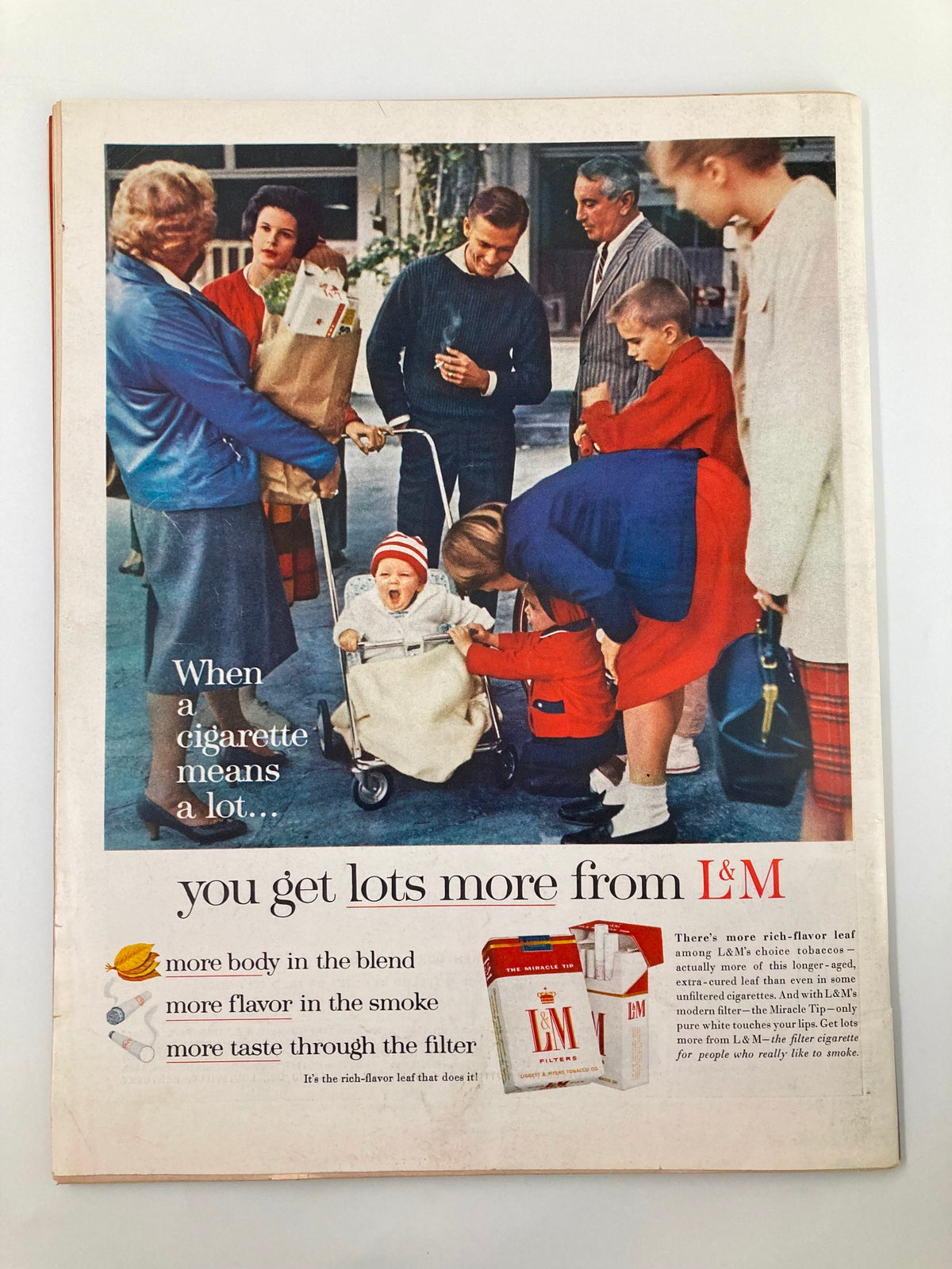Vintage advertisement from VTG Life Magazine April 13, 1962 featuring a family scene with people interacting and a baby in a stroller, promoting L&M cigarettes. The ad includes the slogan "you get lots more from L&M".