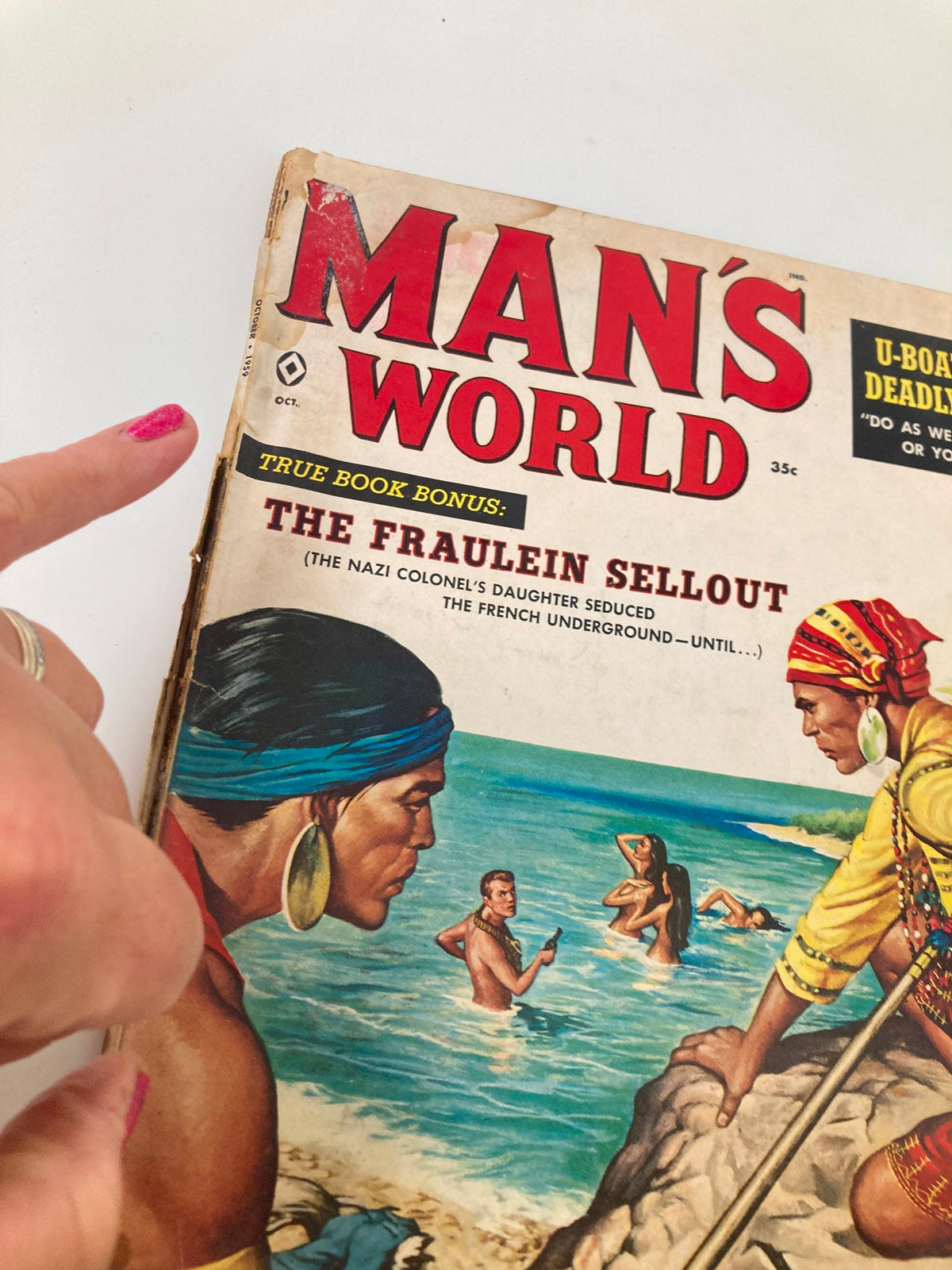 Close-up of the cover of VTG Man's World Magazine October 1959 highlighting the title 'The Fraulein Sellout' and beach scene illustration.