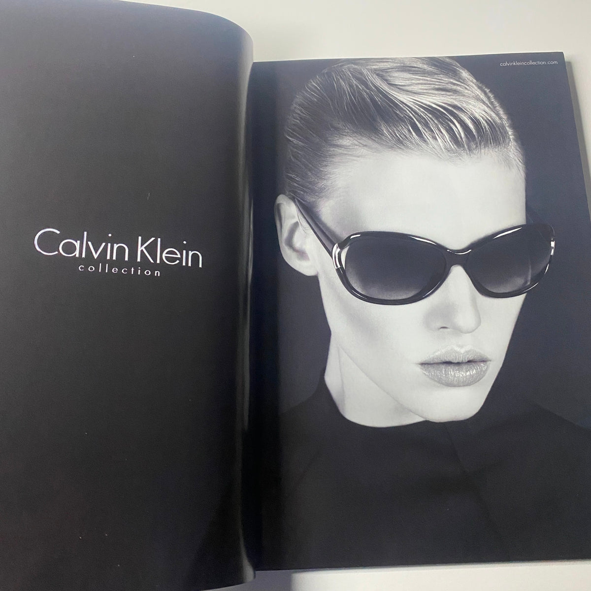 A striking black and white fashion image from Harper's Bazaar Australia Magazine October 2010 showcasing a model in Calvin Klein sunglasses, emphasizing modern elegance and chic style.
