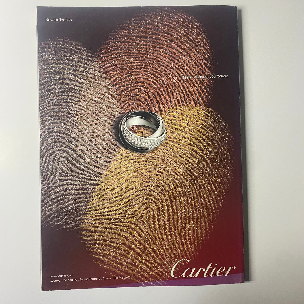An artful advertisement from Harper's Bazaar Australia Magazine October 2010 presenting Cartier jewelry, featuring exquisite rings displayed against a fingerprint design background.