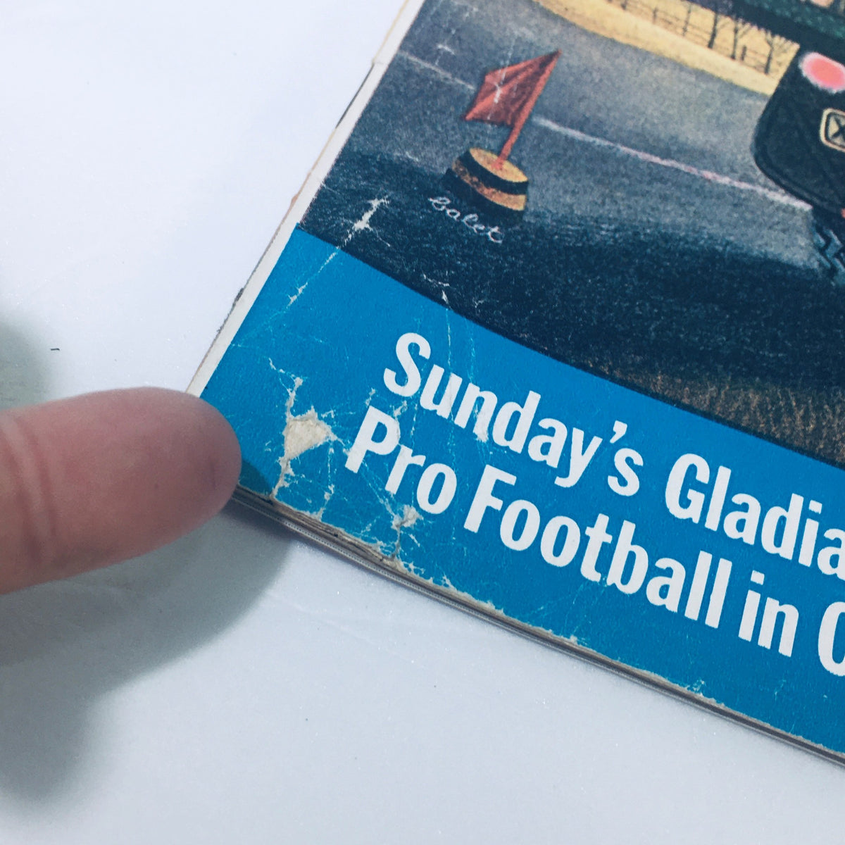 Close-up of the edge of VTG The Saturday Evening Post November 24 1962, highlighting the title 'Sunday's Gladiators: Pro Football in Color' with minor wear and tear, emphasizing its vintage condition.