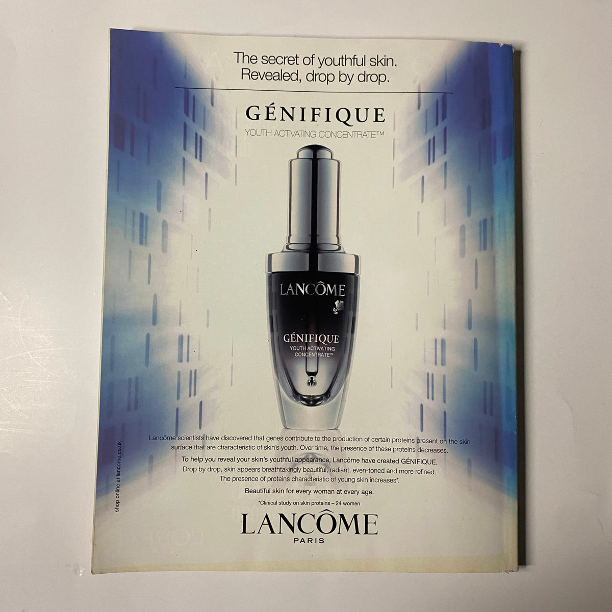 Elle UK Magazine June 2009 Reese Witherspoon Cover: A Lancôme advertisement for Génifique, featuring a sleek serum bottle against a modern, abstract background.