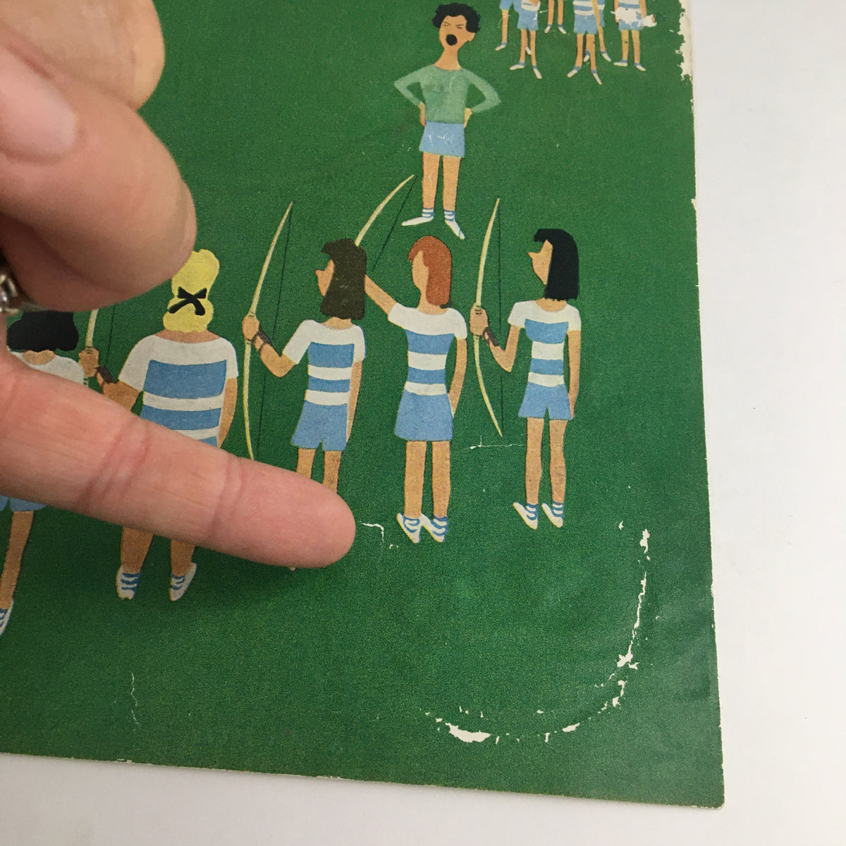 Detailed look at The New Yorker May 12 1956 cover by Charles E. Martin, highlighting the playful depiction of children with bows in a green setting, with a finger pointing for emphasis.