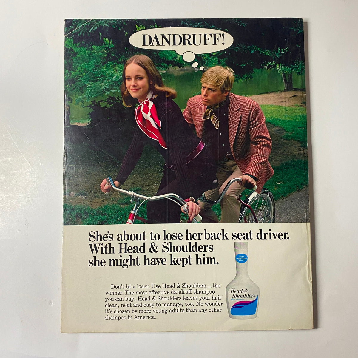 Humorous advertisement from Seventeen Magazine November 1969 promoting Head & Shoulders shampoo with a girl and a boy on bicycles.