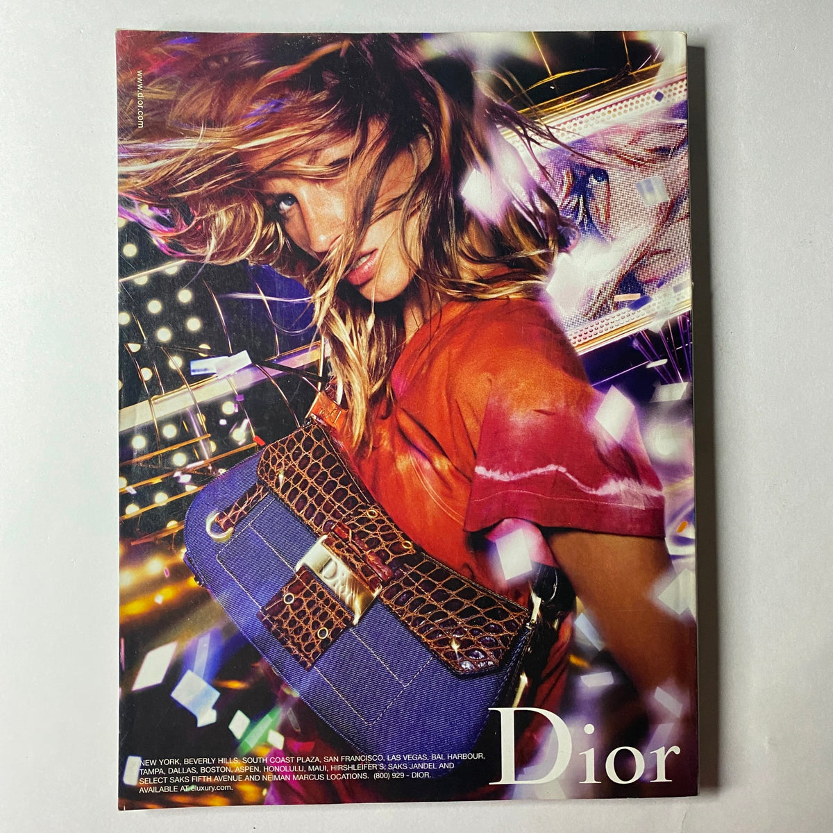 Dior advertisement displaying a model with flowing hair, wearing a vibrant outfit and holding a stylish handbag, set in a colorful and dynamic background. Vogue Magazine – August 2002 – Jennifer Aniston Cover (No Label, Very Good Condition).