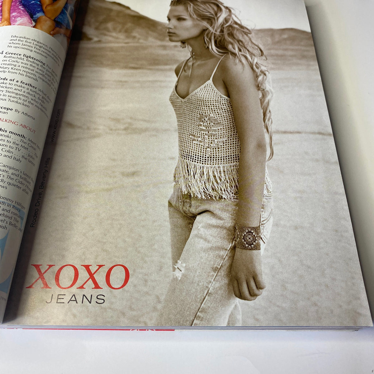 Vogue Magazine December 1999 Gisele Bündchen Cover - A fashion photograph featuring a model in XOXO jeans with a fringed top, showcasing late 1990s style.