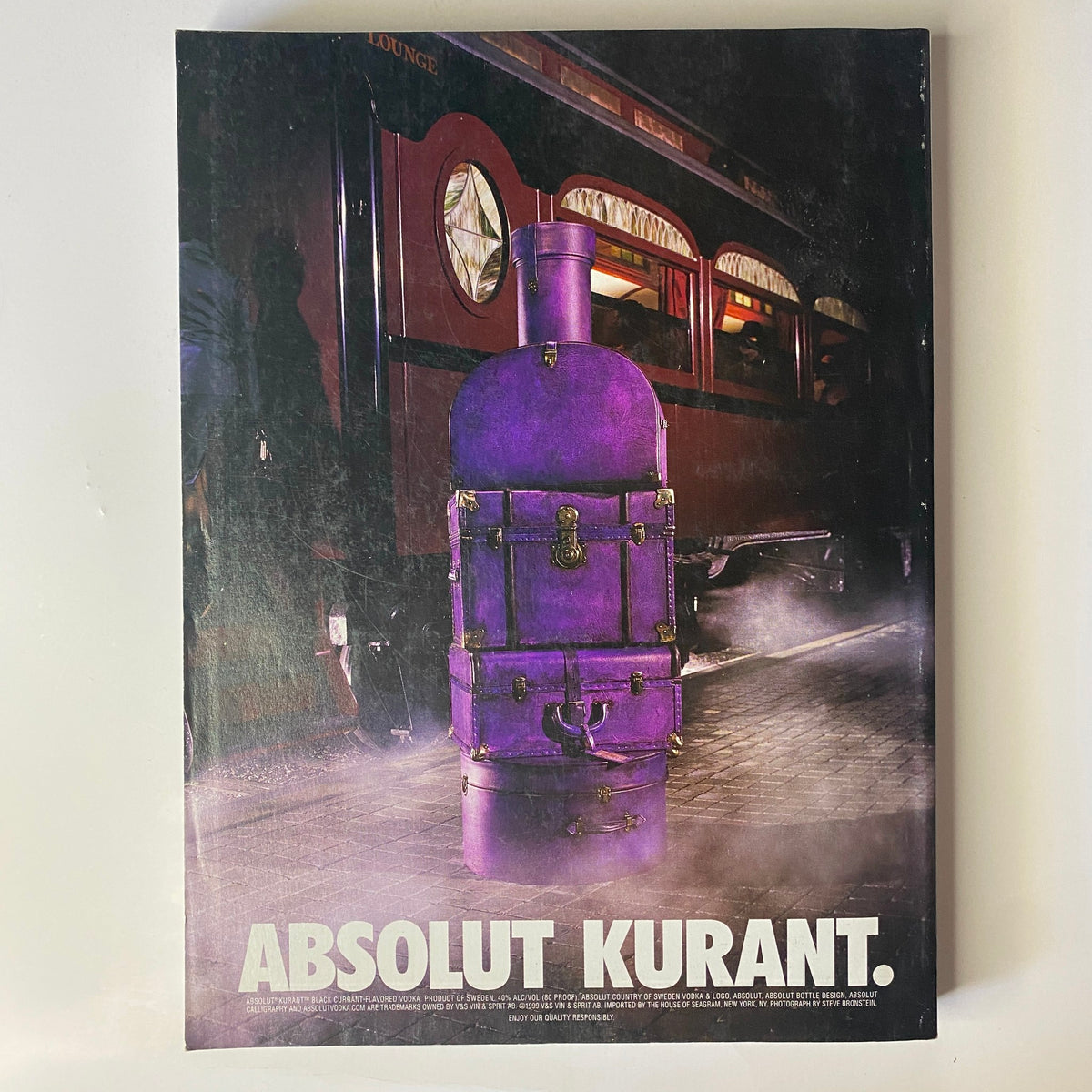 Vogue Magazine December 1999 Gisele Bündchen Cover - A striking advertisement for Absolut Kurant featuring a vintage purple stove, set against a moody, atmospheric background.