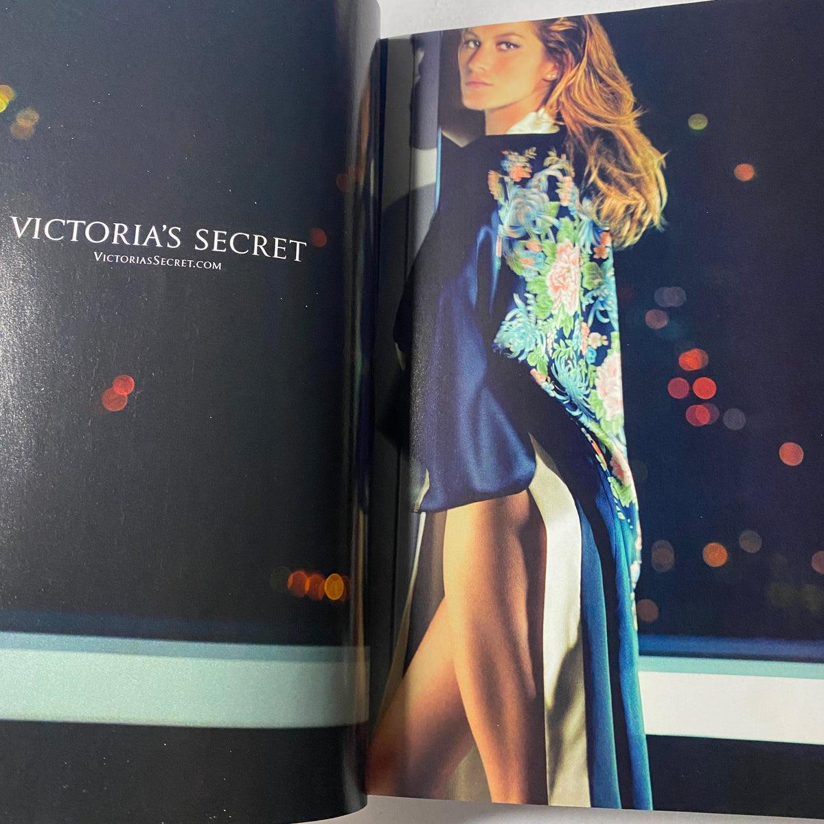 An advertisement page from Vogue Magazine September 2003 featuring a model for Victoria's Secret, highlighting glamorous fashion with a city backdrop in a stylish hair and outfit presentation.