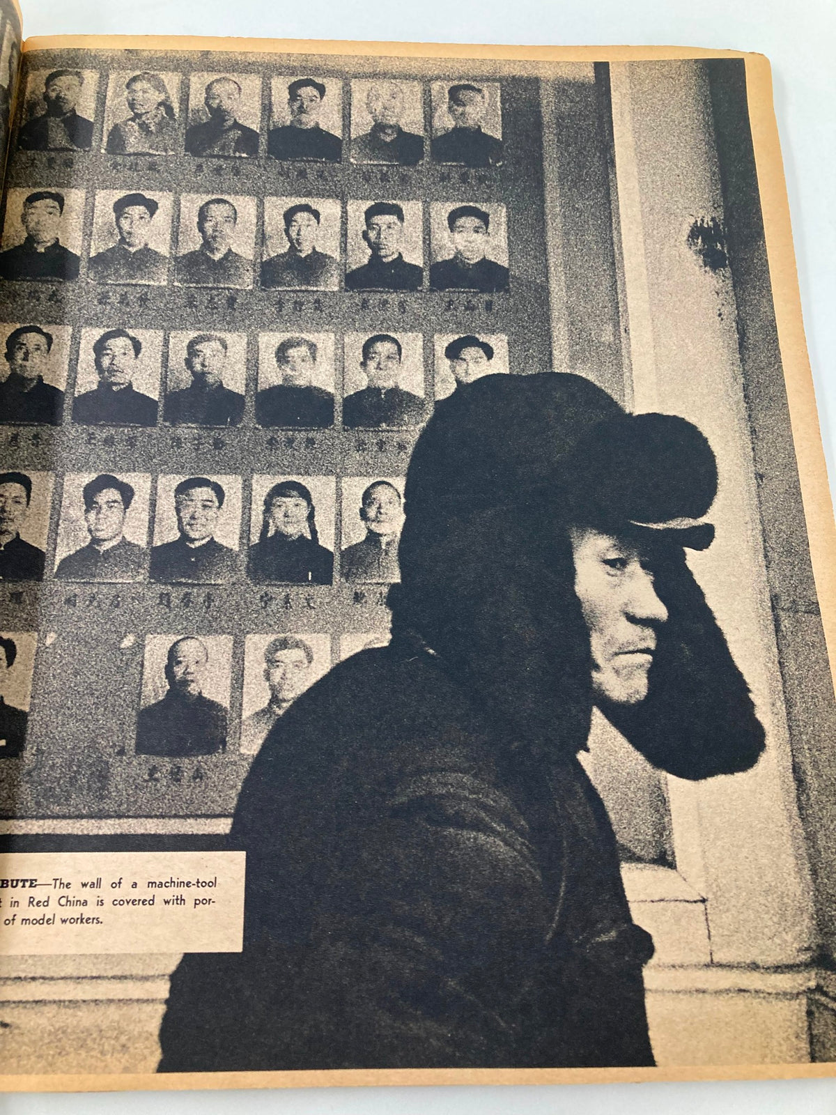 Historical image in VTG The New York Times Magazine May 23 1965 showing a worker in a fur hat in front of a wall filled with black and white portraits of model workers from Red China.