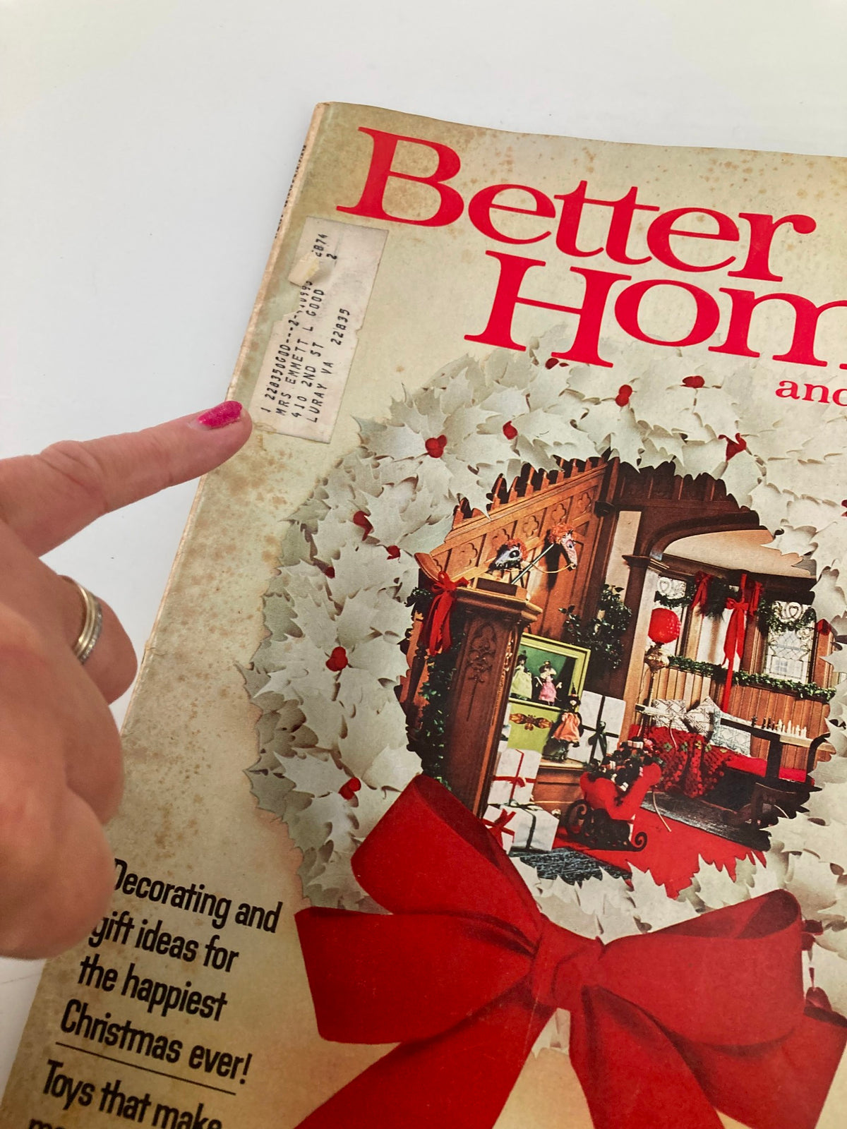 Close-up of the cover of VTG Better Homes and Gardens Magazine December 1973, showing a hand pointing to the title label and festive wreath design.