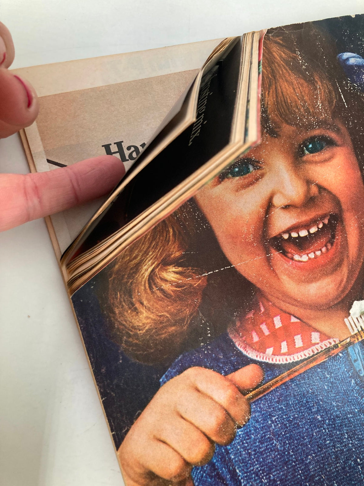 Image of a child happily smiling while holding a playful toothbrush, from the VTG Better Homes and Gardens Magazine December 1973, illustrating joyful holiday moments.