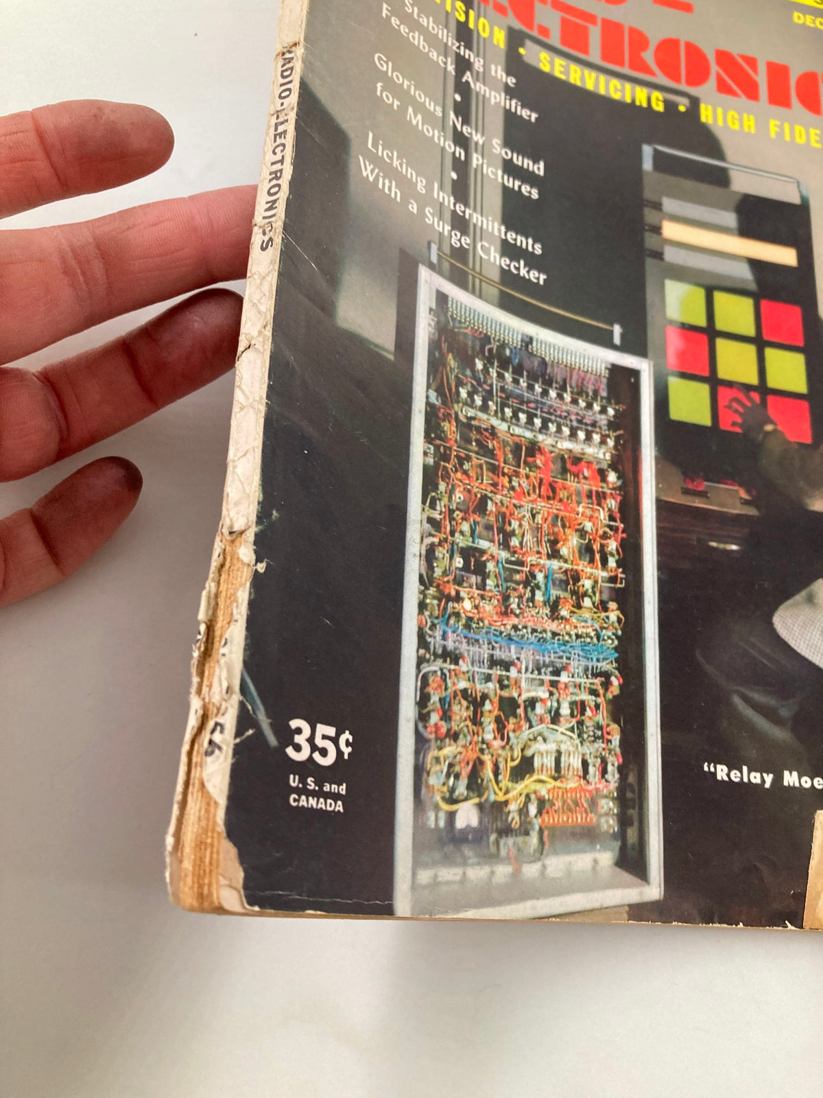Side view of the cover of VTG Radio-Electronics Magazine December 1956, indicating wear and showing the title 'Relay Moe' Plays Tick-Tack-Toe along with electronic components.