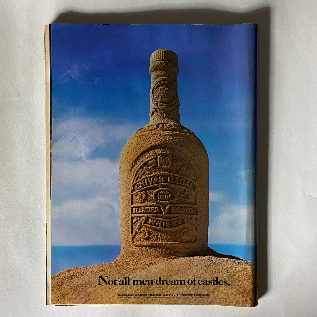 Advertisement page from the Vintage Sports Illustrated magazine February 15, 1988, featuring a creative sand sculpture of a Chivas Regal whisky bottle. A distinctive piece reflecting advertising trends of the era.