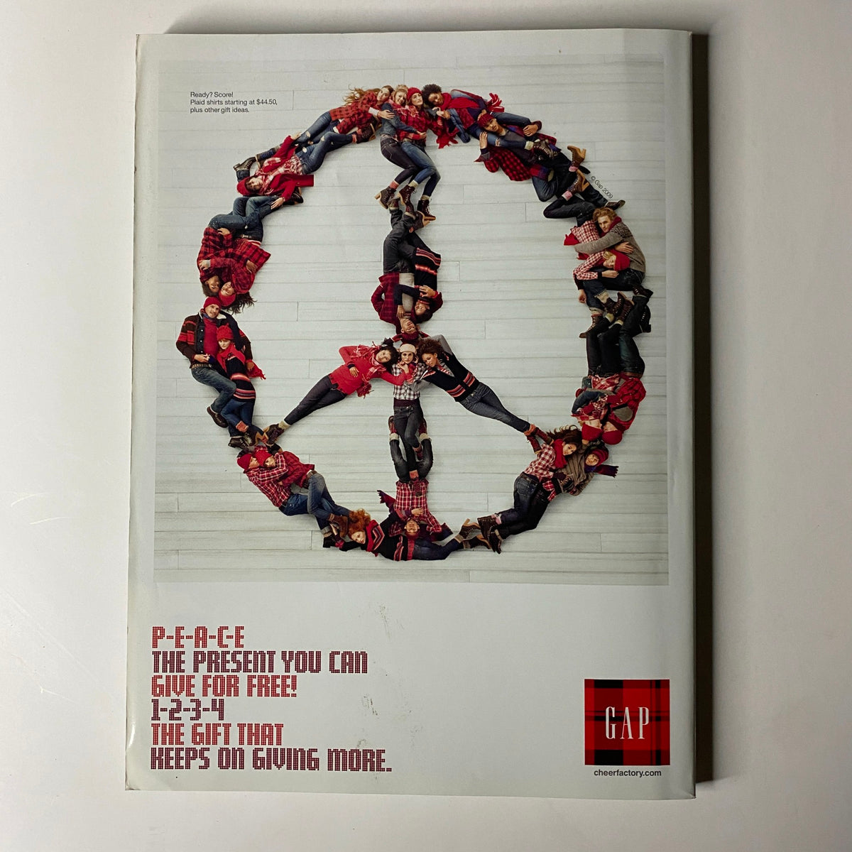 A Gap advertisement from Vogue Magazine December 2009 depicting a group of models arranged in a peace sign, promoting a message of peace and community during the holiday season.