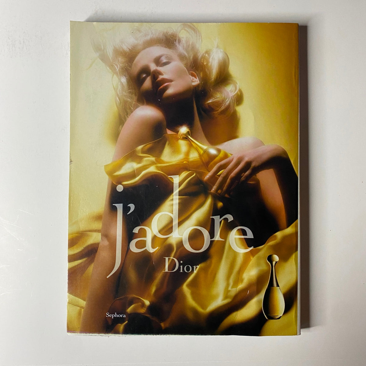Cover of Dior's J'adore fragrance ad featuring a glamorous model styled in luxurious fabric, presented in Vogue Magazine October 2004.