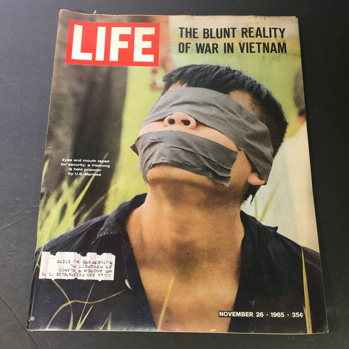 VTG Life Magazine November 26 1965 cover featuring a poignant image related to the Vietnam War, titled 'The Blunt Reality Of War In Vietnam'. A young man has his eyes and mouth taped shut, symbolizing the harsh realities of conflict.
