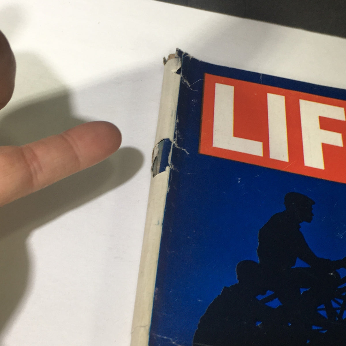 Close-up view of the spine of VTG Life Magazine December 20 1963 - Special Double Issue on The Movies, showcasing wear and a finger pointing to a damage spot.