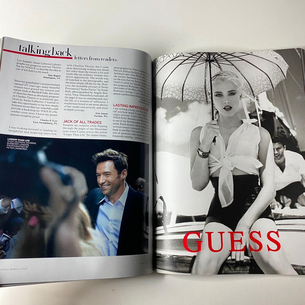 Inside spread of Vogue Magazine March 2012 featuring letters from readers, a smiling Hugh Jackman, and a black and white Guess advertisement featuring a model in a swimsuit.