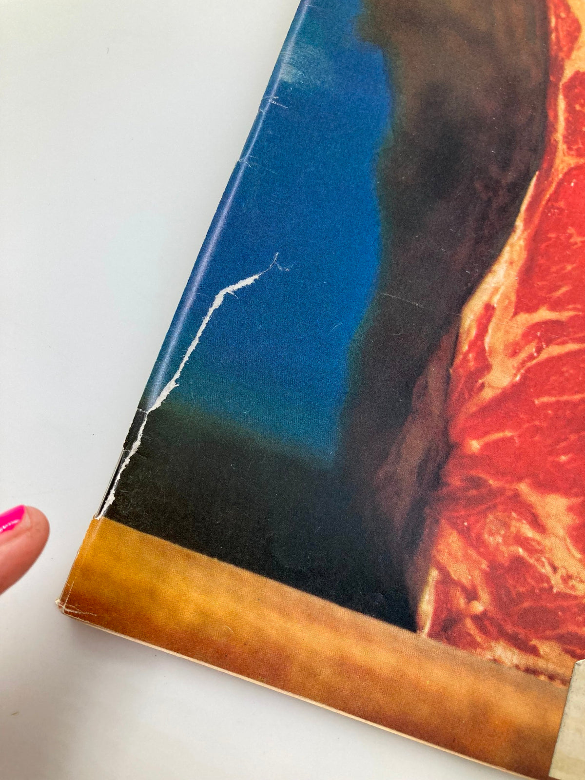 Close-up of the edge of the vintage Newsweek Magazine dated April 9, 1973, The Meat Furor Issue, showing minor wear and tear typical of its age, with visible creases and rips, highlighting the magazine's historical significance.