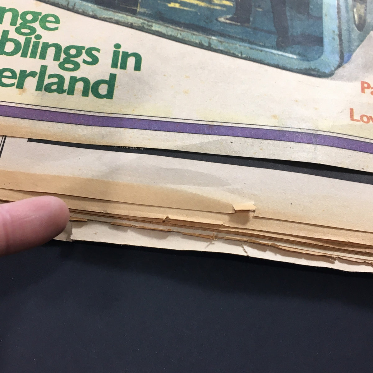 Detailed shot of the vintage Rolling Stone magazine from October 24, 1974, showing the wear on the pages and a finger pointing, emphasizing the magazine's age and character.