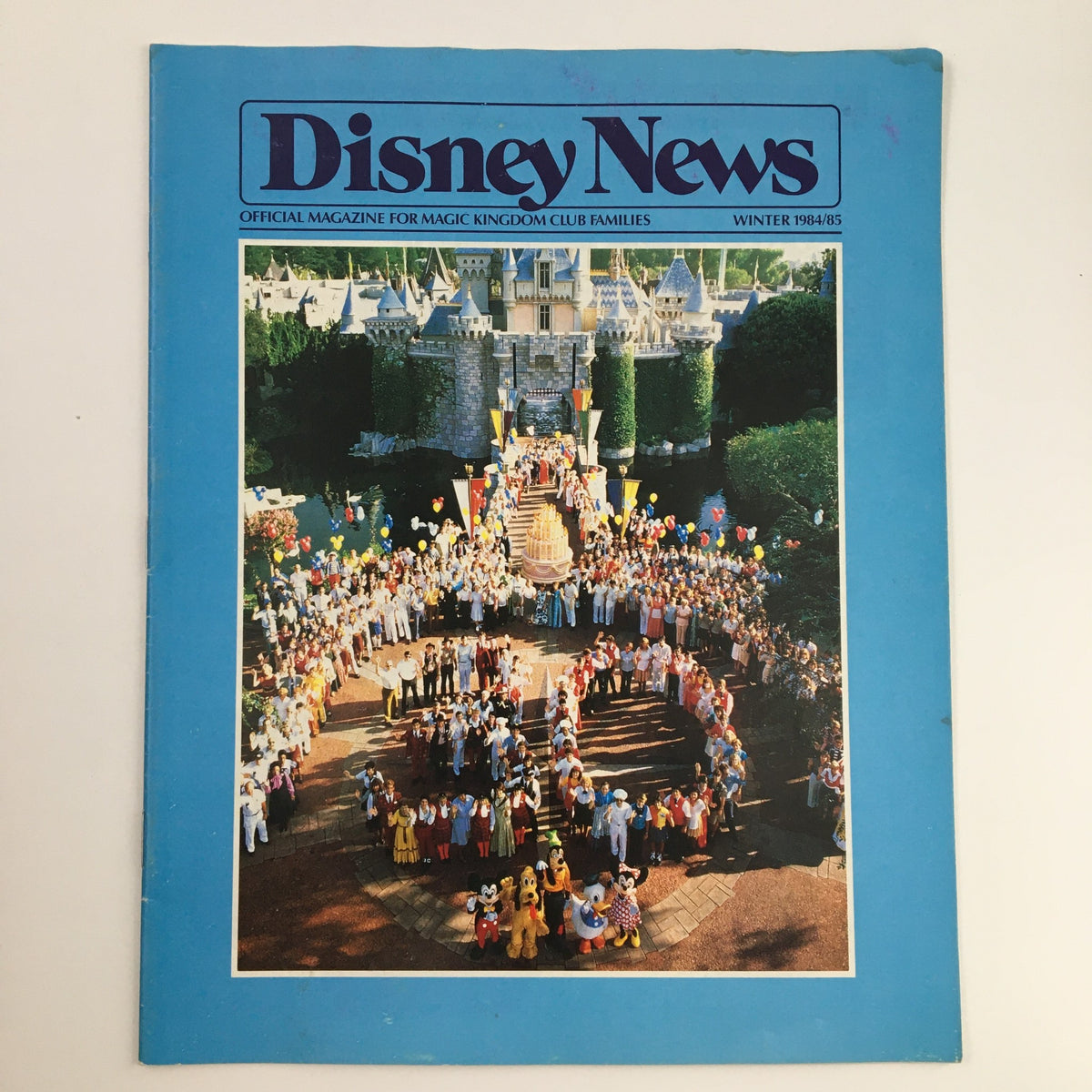 Disney News Magazine Winter 1984 cover featuring a vibrant celebration at Sleeping Beauty Castle with Disney characters and balloons.